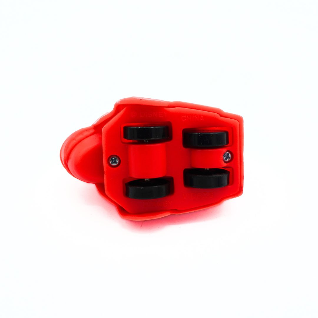 A close-up of a red plastic mechanical component, likely a roller skate bushing or bearing assembly, showing four black circular rollers held by screws, on a white background.