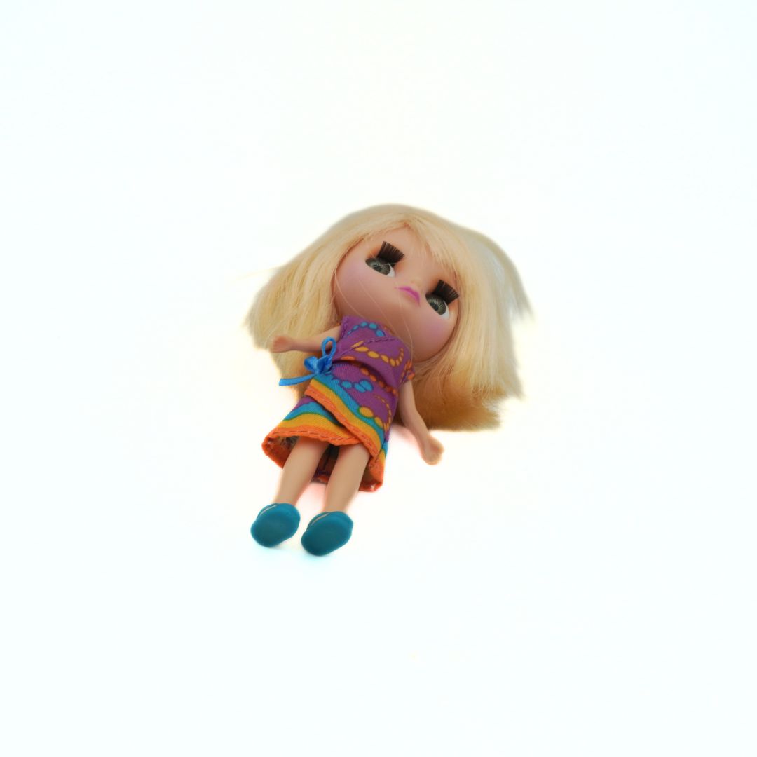 Toy doll with blonde hair and colorful outfit on a white background