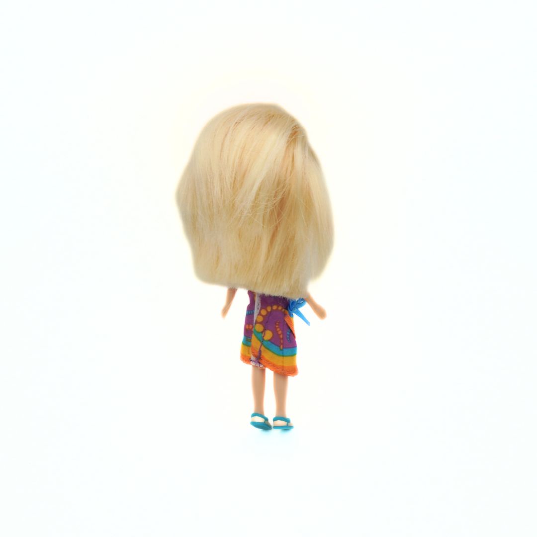 Small doll with blonde hair and a colorful dress on a white background