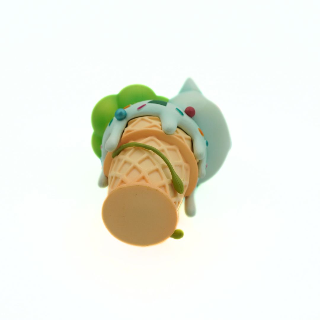 Toy ice cream cone with a green cherry on top against a white background