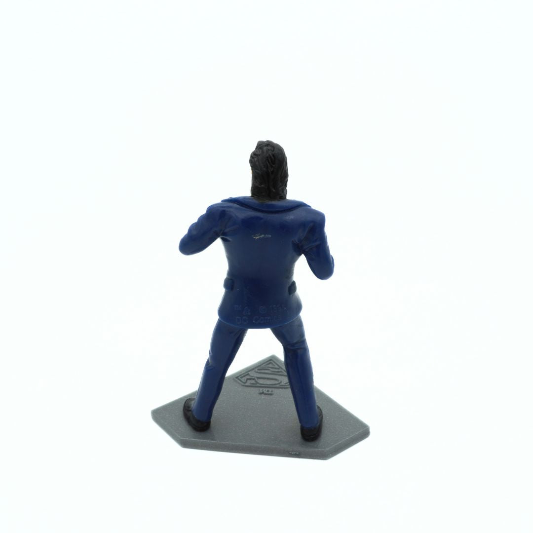 Back of a vintage 90s Clark Kent transforming into Superman figurine on a grey stand