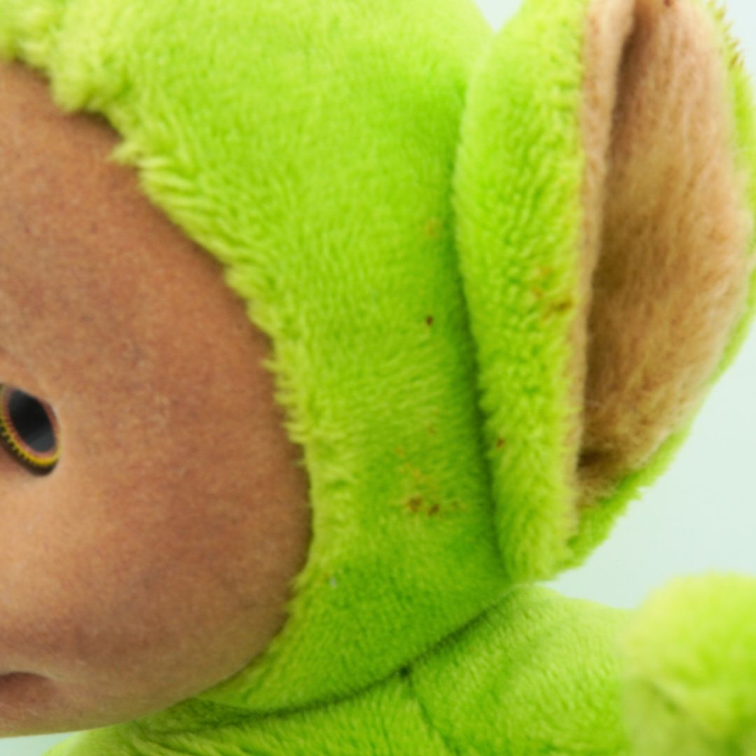 Close-up of a green plush toy with a brown face and ears.