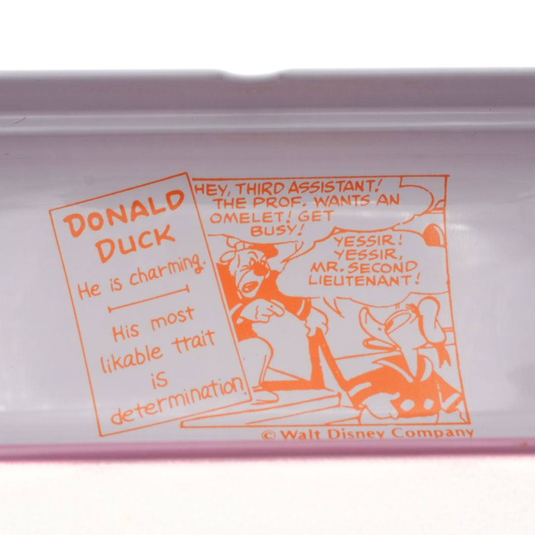 Closeup of the inside of a vintage Donald Duck pencil case showing an orange print design