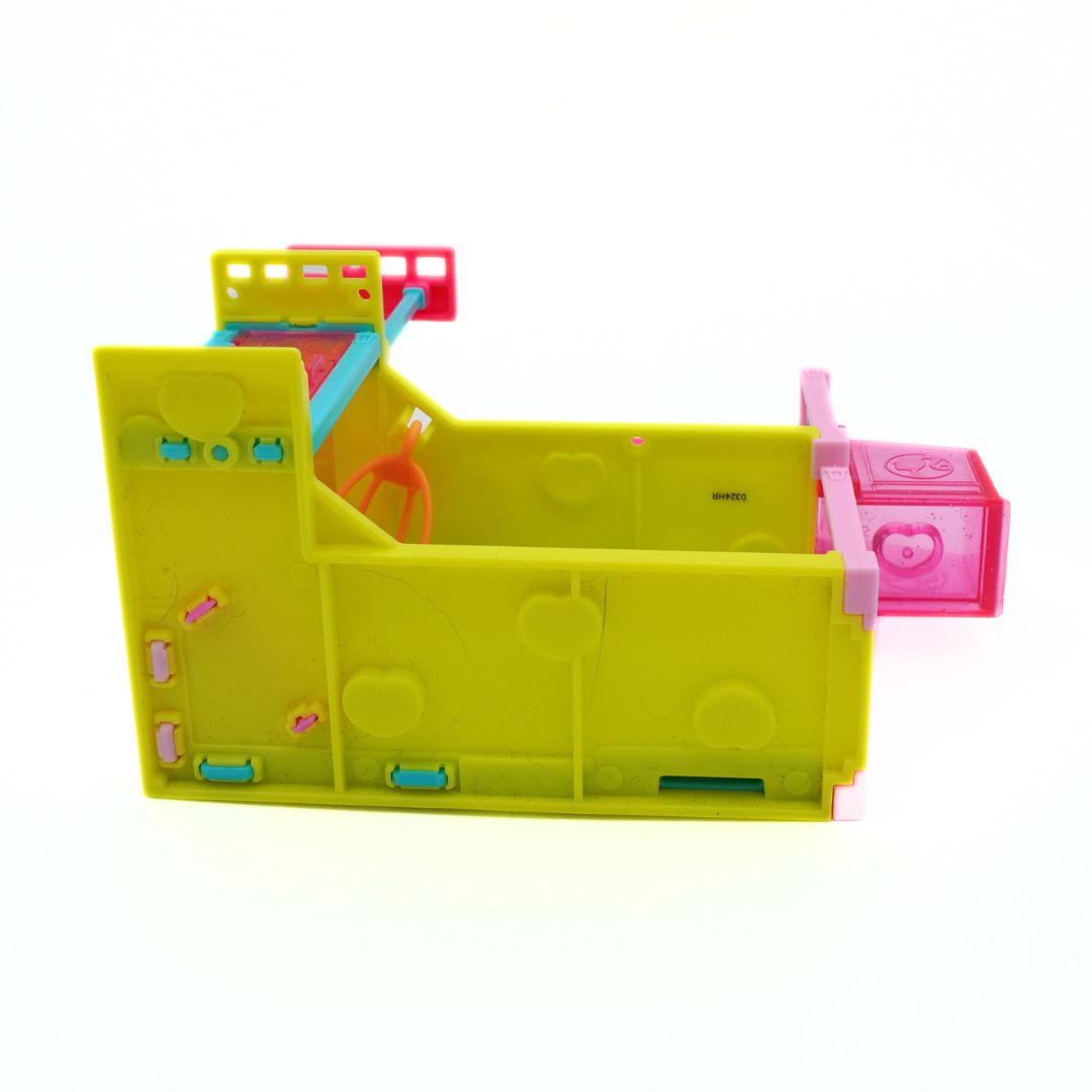 A bright lime green plastic toy structure with pink, orange, and blue accessories, photographed on a seamless white background.