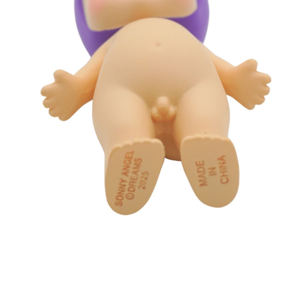 Close-up of the back of a vinyl collectible figure, showing the beige skin tone, purple hair, and printed text on the soles of the feet reading 'SONNY ANGEL DREAMS 2025' and 'MADE IN CHINA'.
