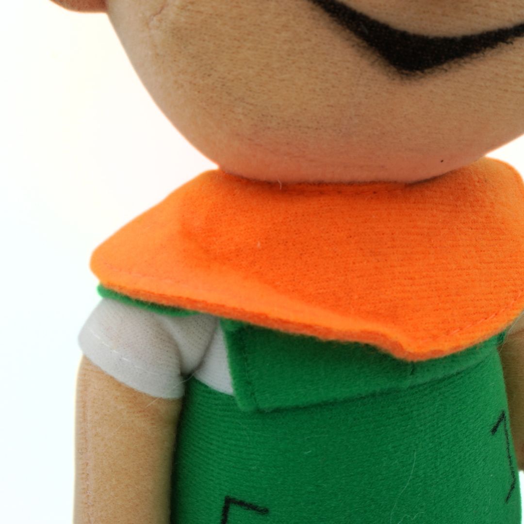 Close-up of a plush toy with an orange collar and green outfit on a white background
