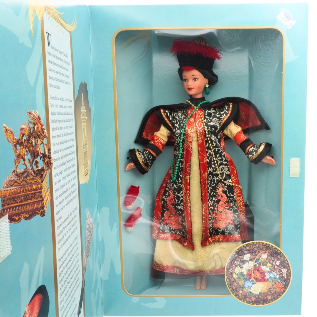 Doll in traditional outfit inside a blue box with decorative elements