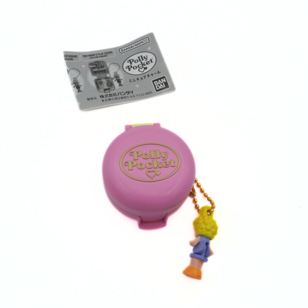 Pink Polly Pocket toy with a character charm and packaging on a white background