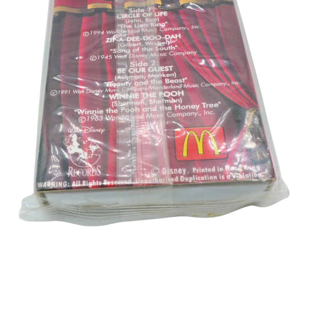 A sealed plastic-wrapped cassette tape, featuring red and black striped cover art with printed track listings and the McDonald's logo.