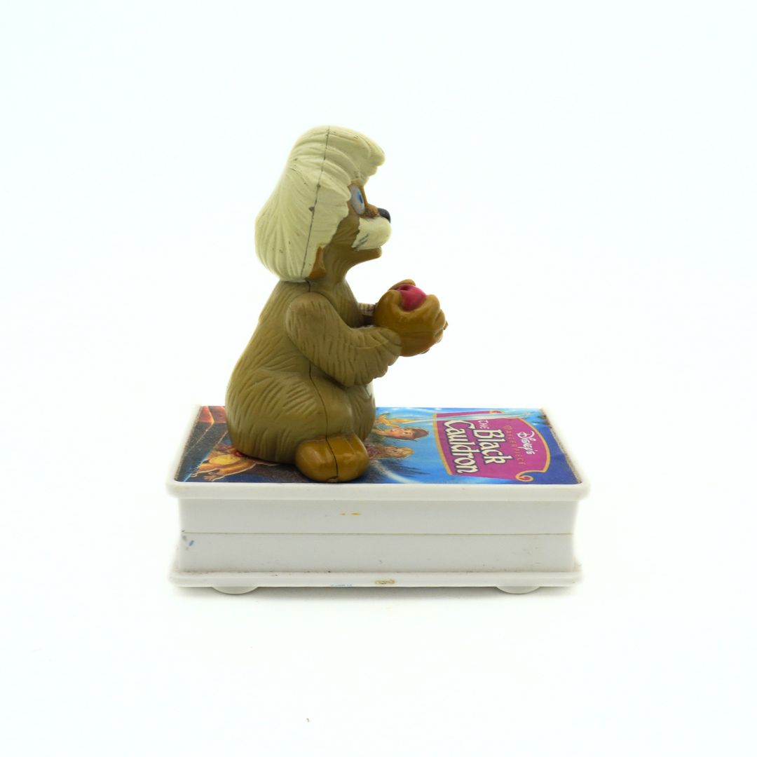 A vintage 90s McDonalds toy of Gurgi sitting on a VHS-shaped stand of The Black Cauldron