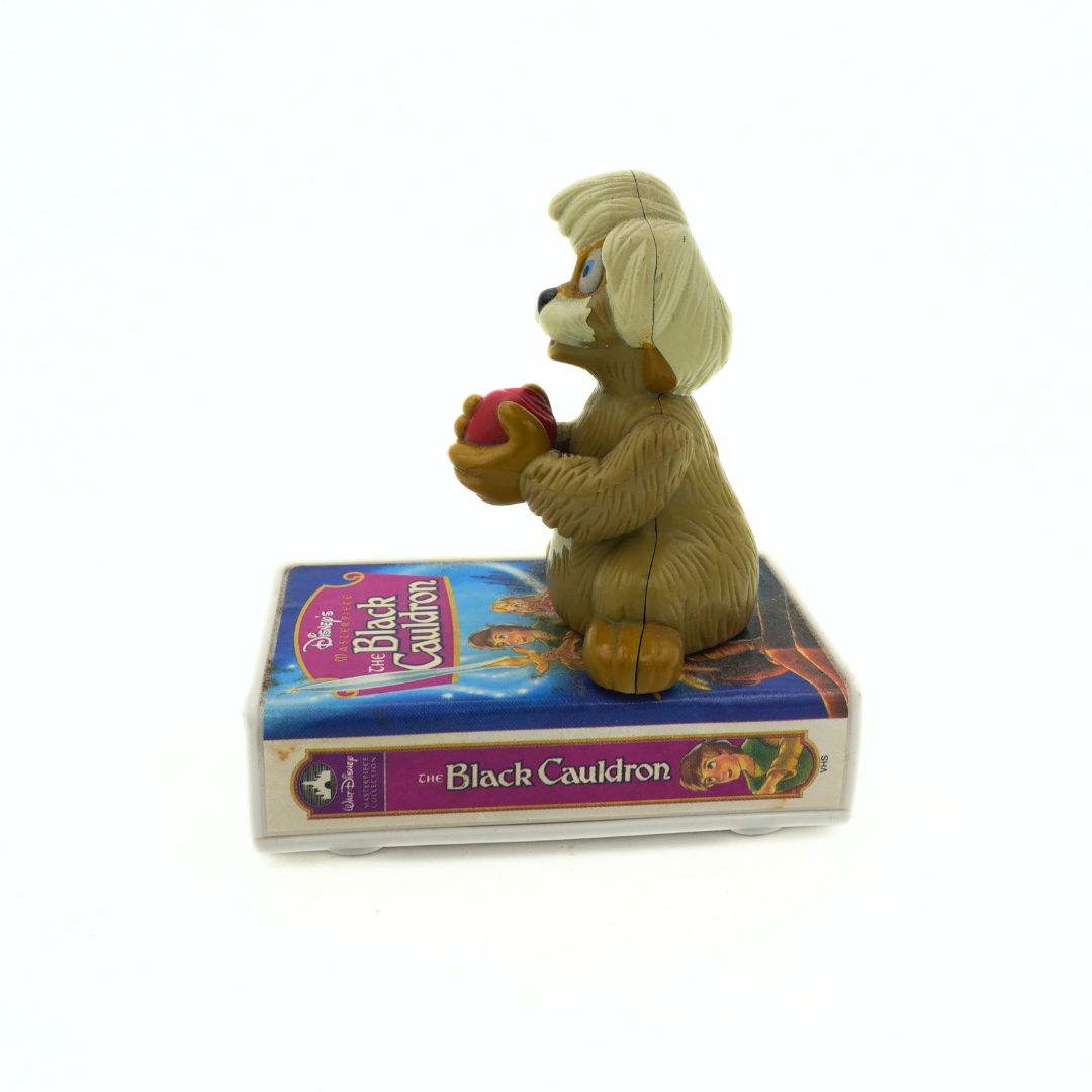 A vintage 90s McDonalds toy of Gurgi sitting on a VHS-shaped stand of The Black Cauldron