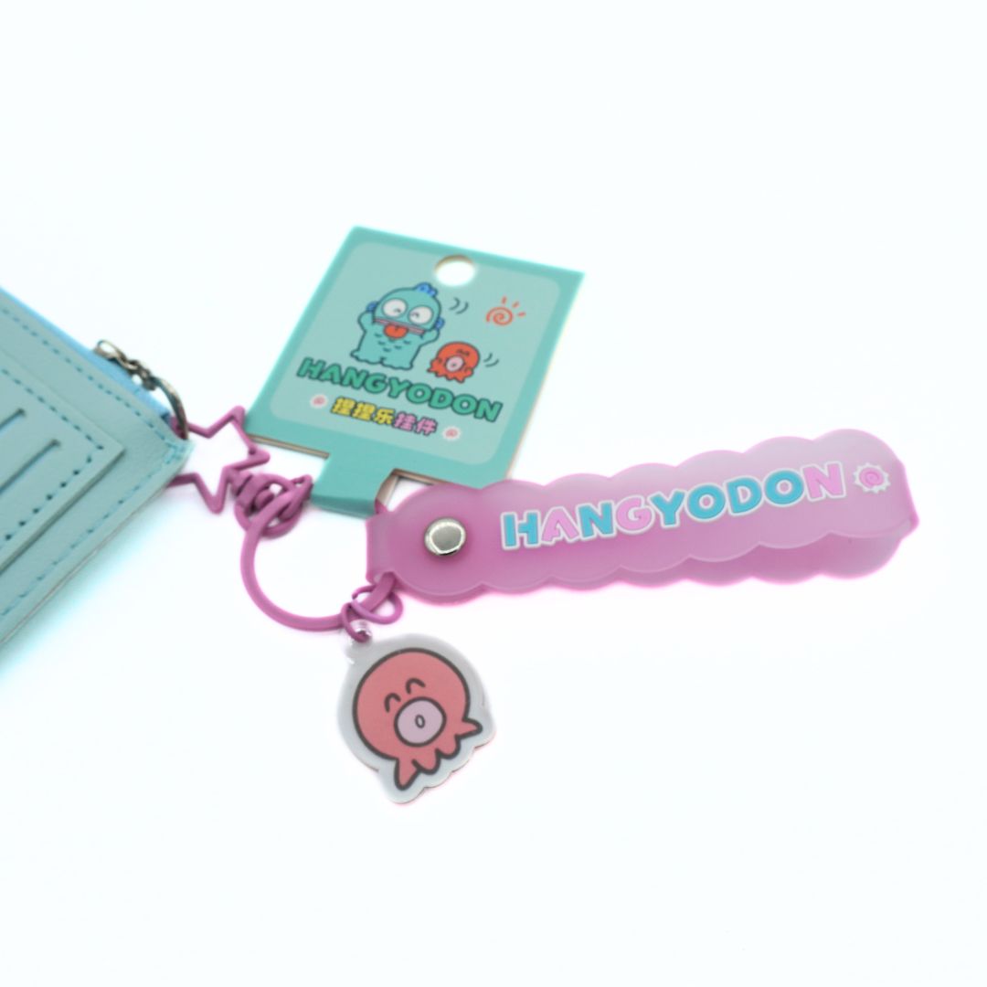 A pink Hangyodon keychain with a scalloped rubber tag, a pink octopus charm, and a light blue zippered pouch on a white background.