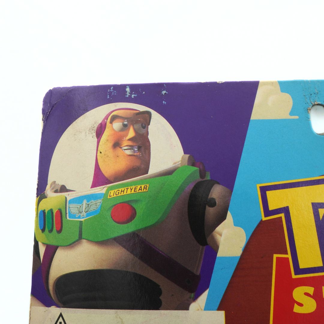 Left corner of a 1995 Toy Story Woody toy showing an illustration of Buzz Lightyear and some wear