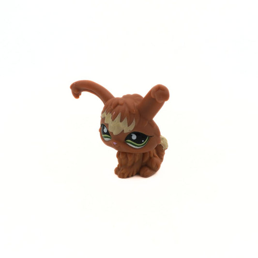 Small brown figurine with large eyes on a white background