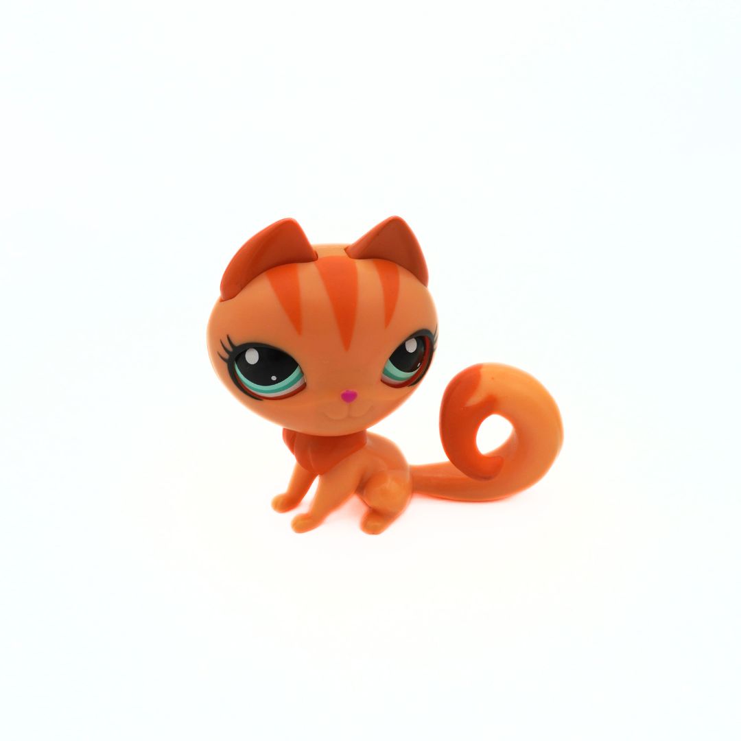 Small orange cat figurine with green eyes on a white background