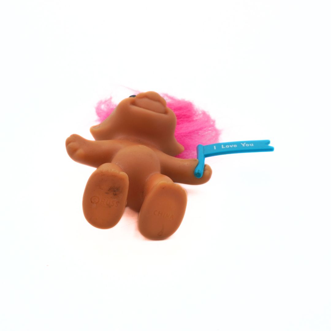 Toy figure with pink hair and a blue ribbon on a white background