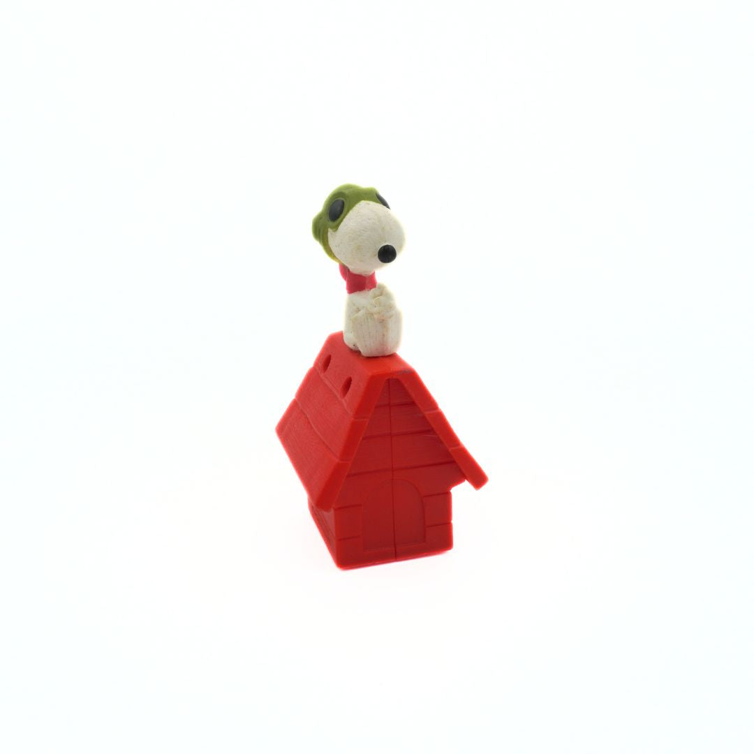 Snoopy figurine on a red doghouse against a white background
