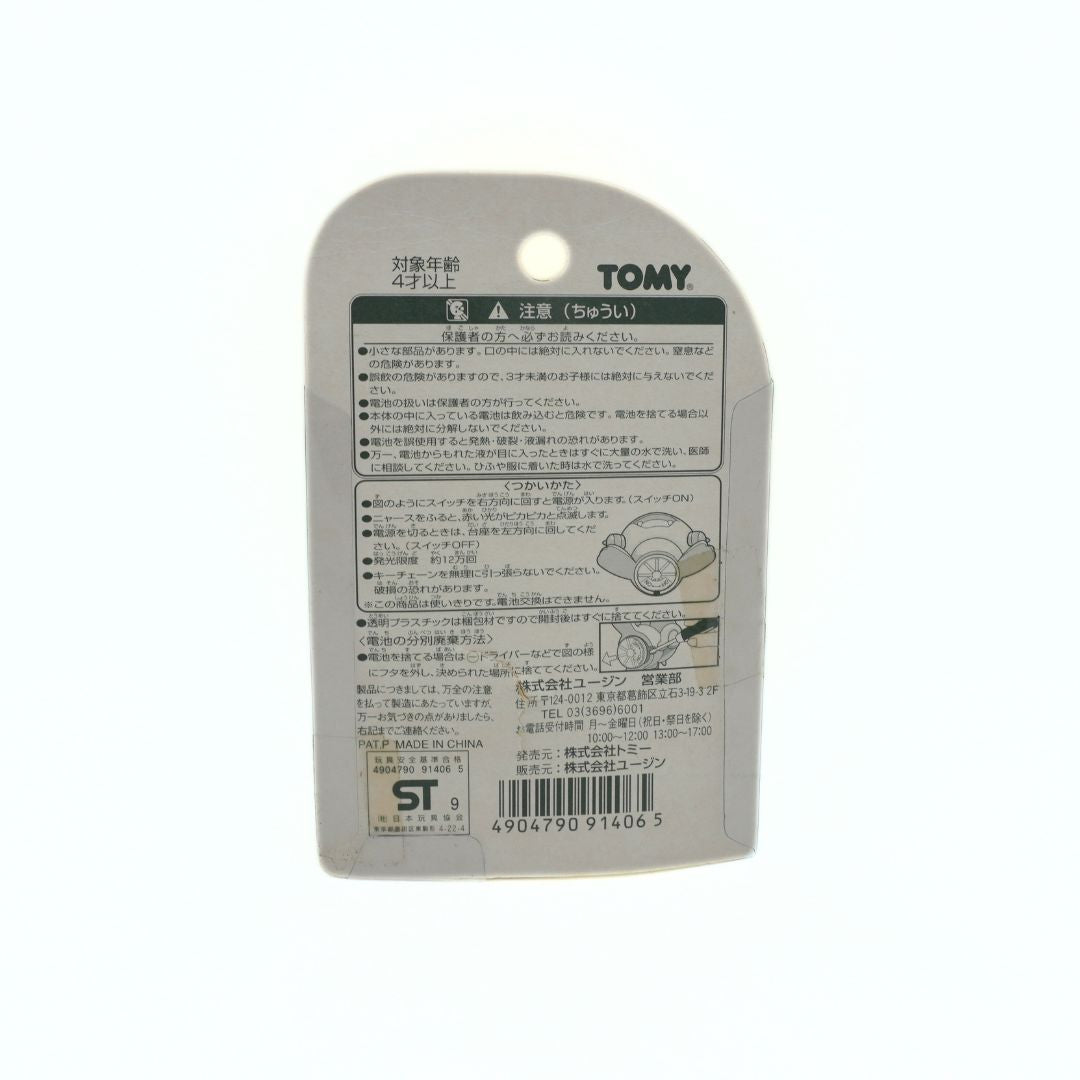 Back of a Tomy product packaging with text and a barcode on a white background