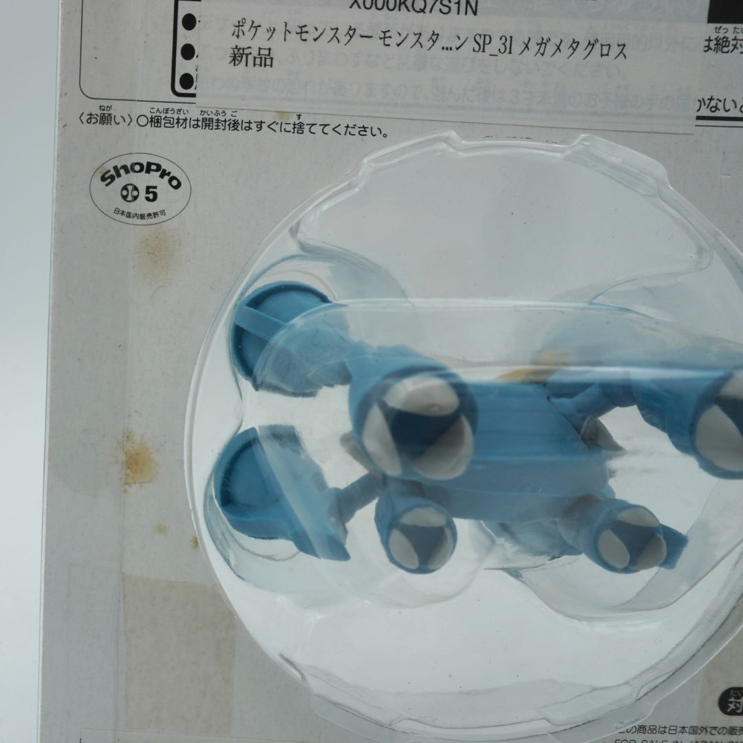 Blue and white toy figure in clear plastic packaging on a white background with text.