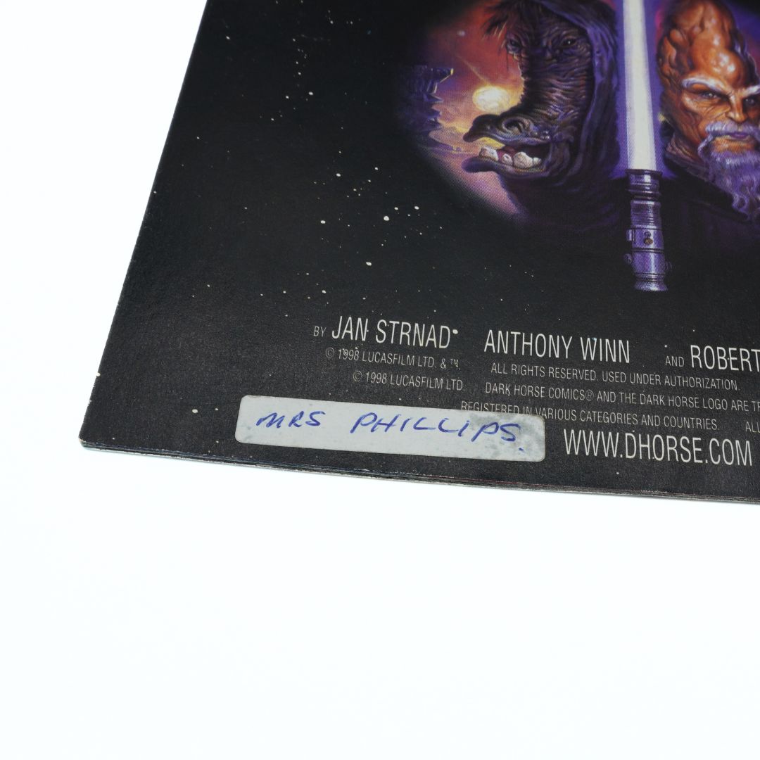 Comic book cover with characters and text, featuring a signature on the bottom right corner.