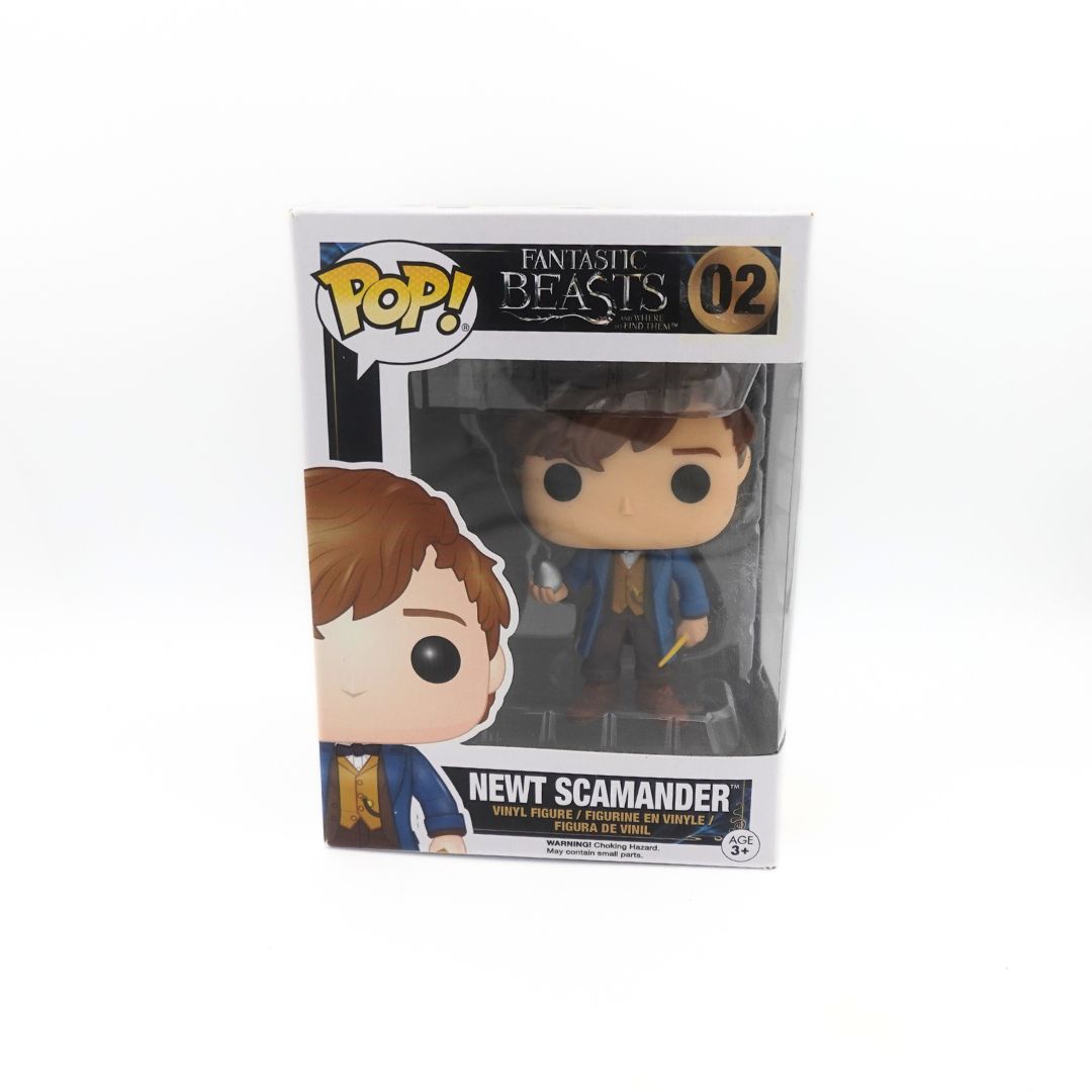 Photo of the Newt Scamander Funko Pop holding a wand and silver egg, wearing a blue jacket
