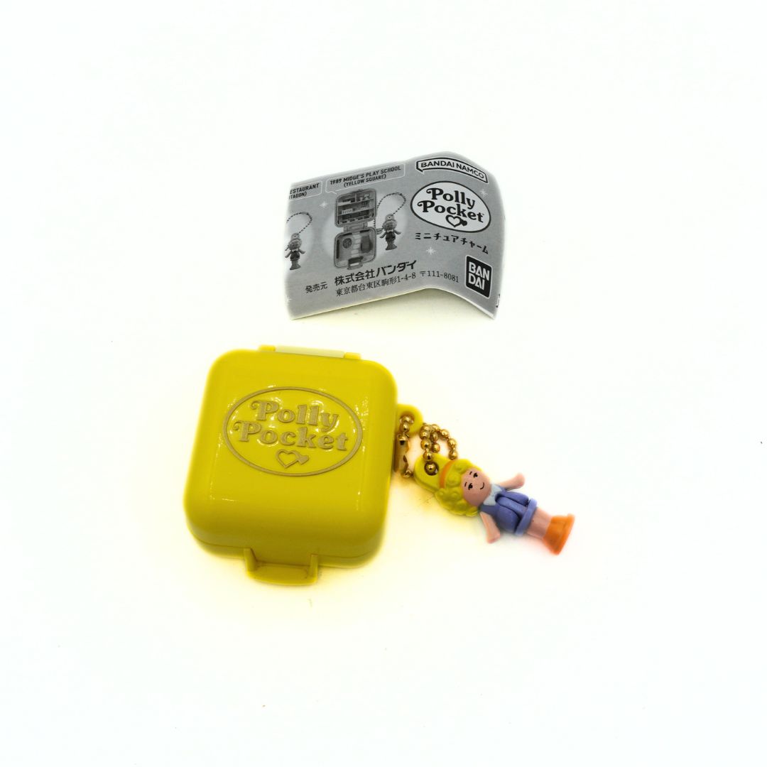 Yellow Polly Pocket toy with a character figure on a white background