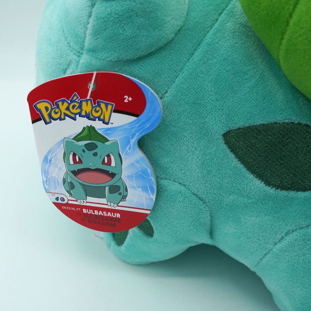 Green plush toy with Bulbasaur tag on a light blue background