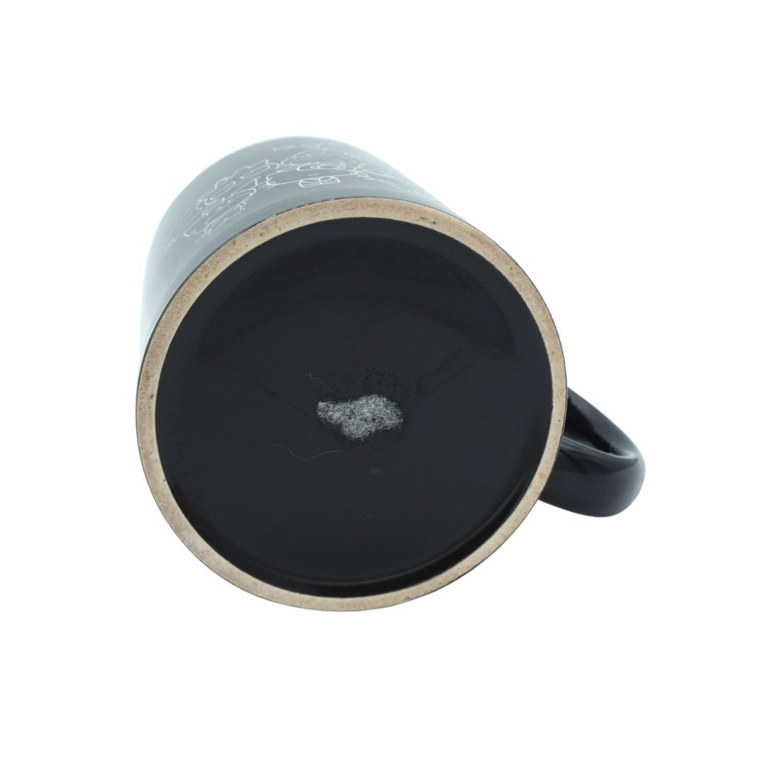 A black ceramic mug shown from a top-down angle, revealing a black interior with a small white speck and a light beige rim, on a white background.