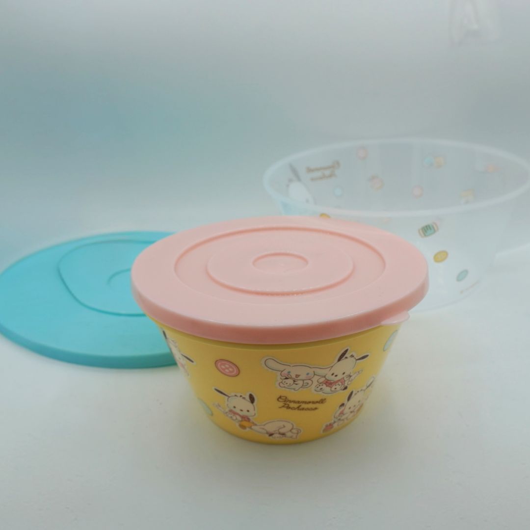 A yellow and pink bowl featuring Cinnamoroll and Pochacco photographed on a white backdrop