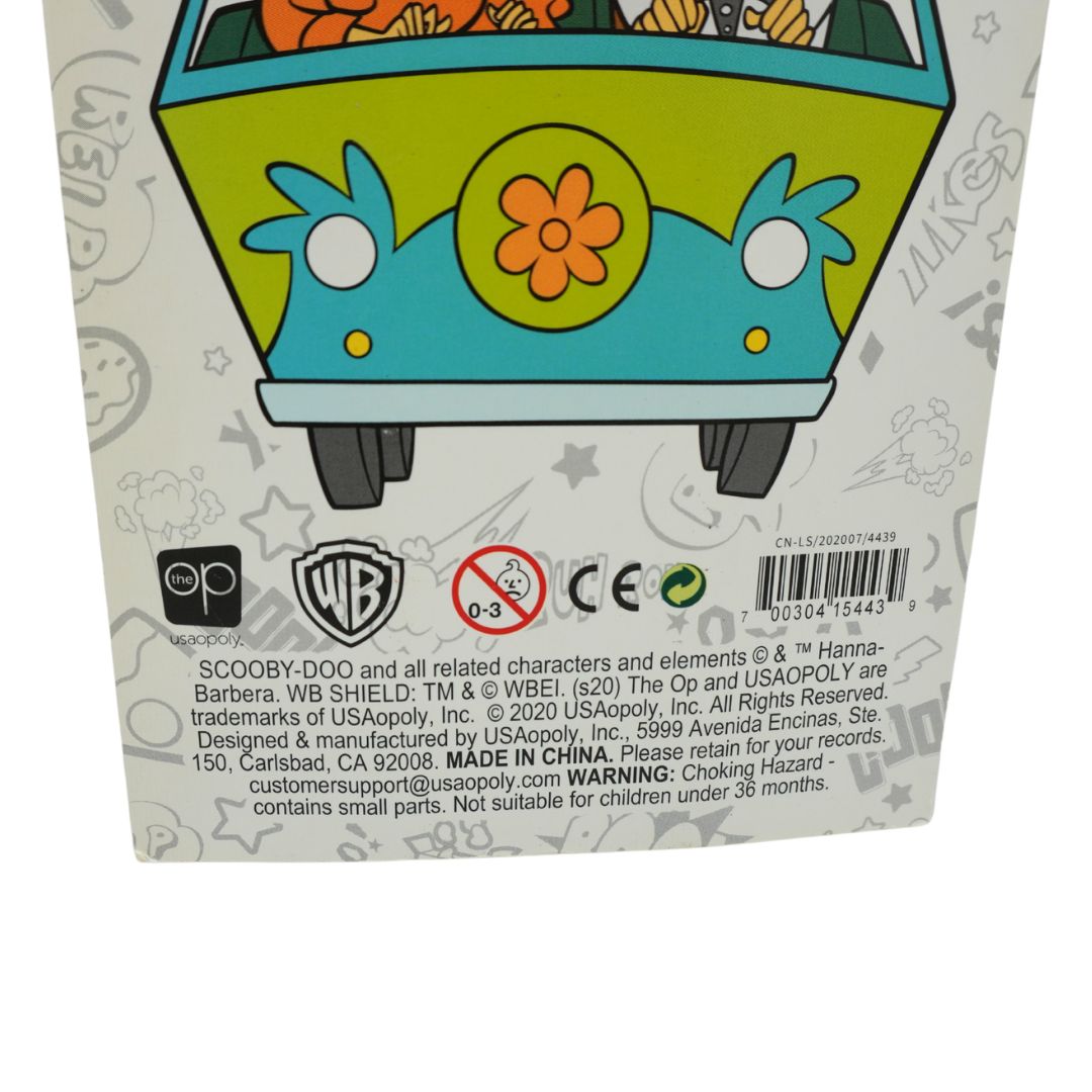 Close-up of the back of a Scooby-Doo product box showing a colorful cartoon van illustration, warning text, barcodes, and Warner Bros. and USAopoly logos on a white background.