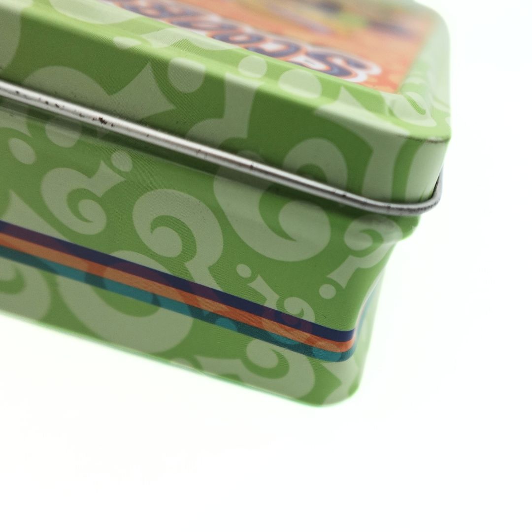 Dint to the side corner of a vintage green Scooby Doo tin with a green, purple and orange colour palette