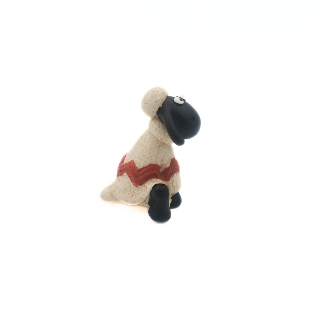 Side on photo of a Shaun the Sheep from the Wallace & Gromit film series wearing a white and red sweater