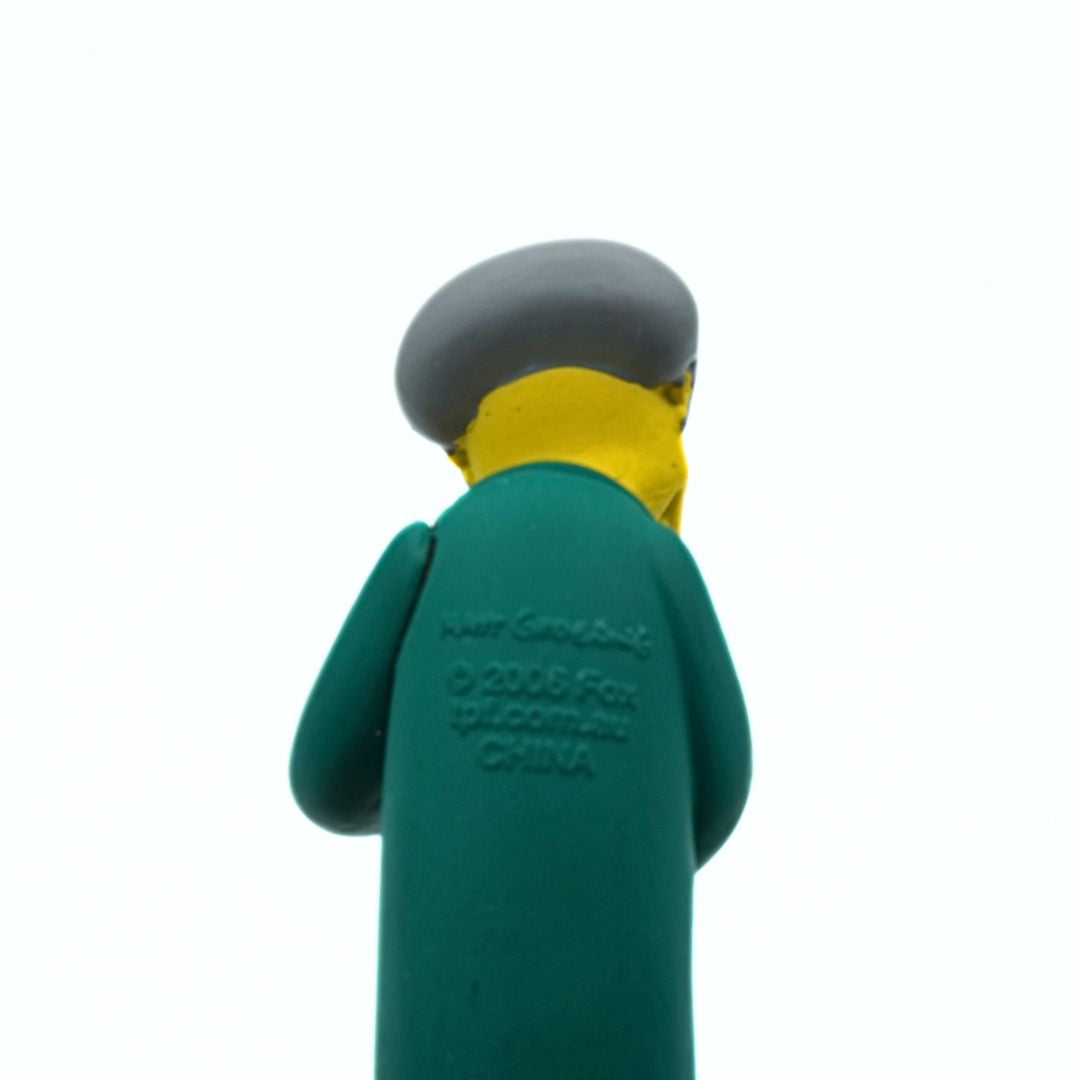 Toy figure with gray hair and teal coat on a white background