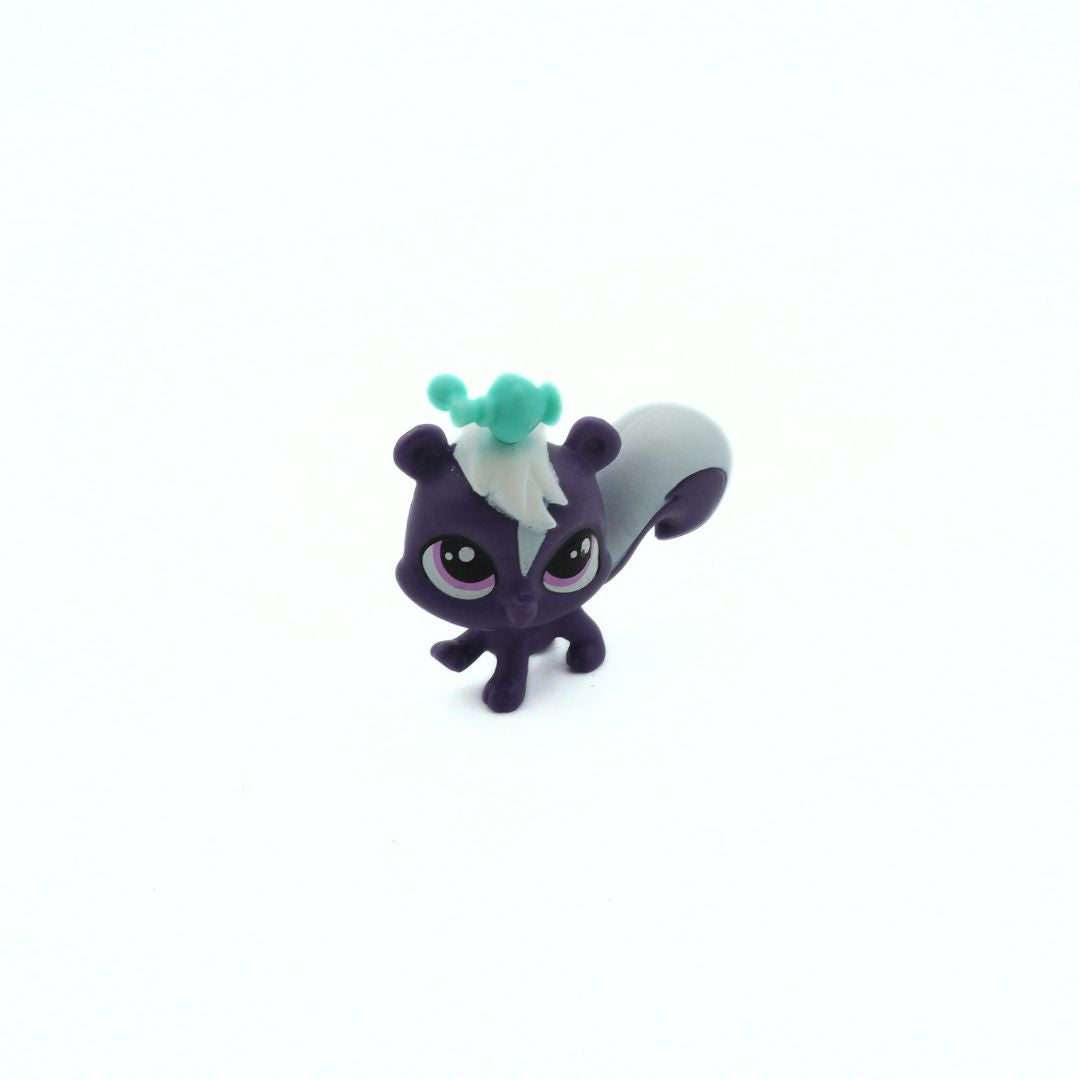 Small figurine of a creature with purple body, white face, and green tuft on a white background