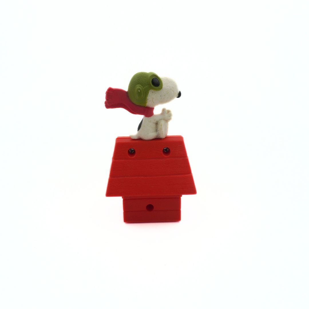 Snoopy figurine with a red doghouse on a white background