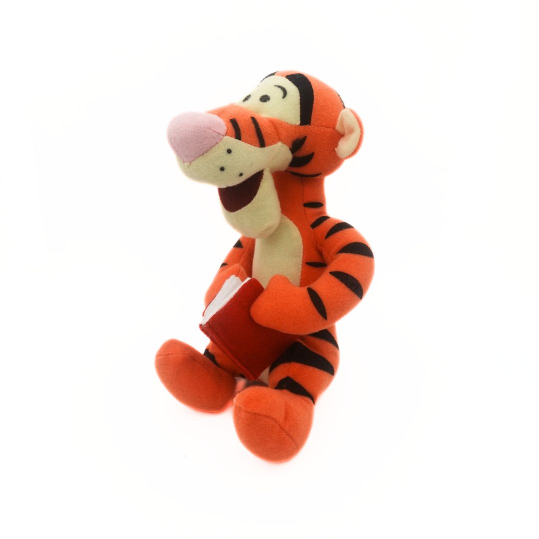 Winnie the Pooh's Tigger plush holding a red book