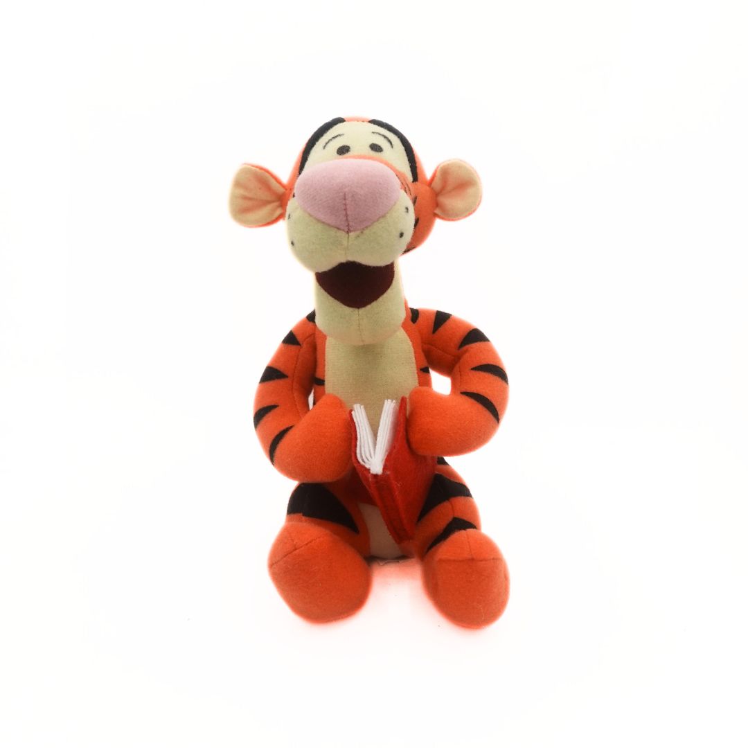 Winnie the Pooh's Tigger plush holding a red book
