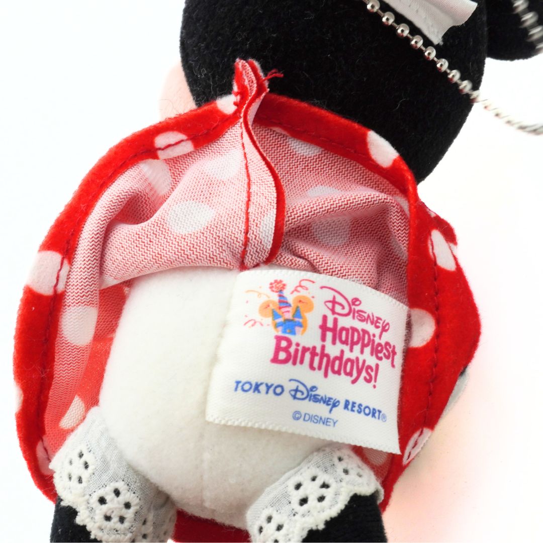 Close-up of a Minnie Mouse plush toy with a red polka dot bow and Disney label on a white background
