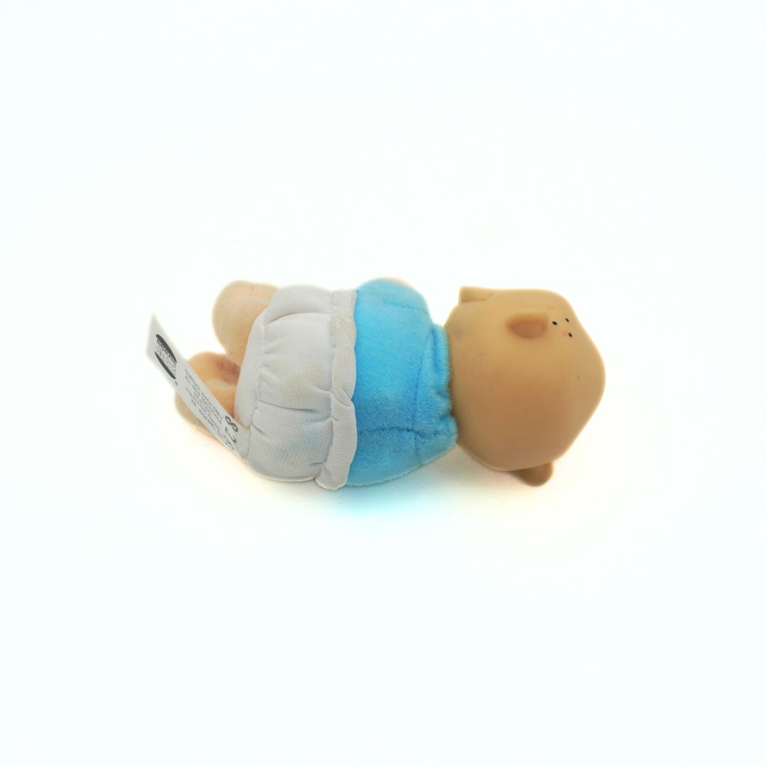 A 90s Tommy Rugrats toy with a solid plastic head and a soft plush body seen from behind