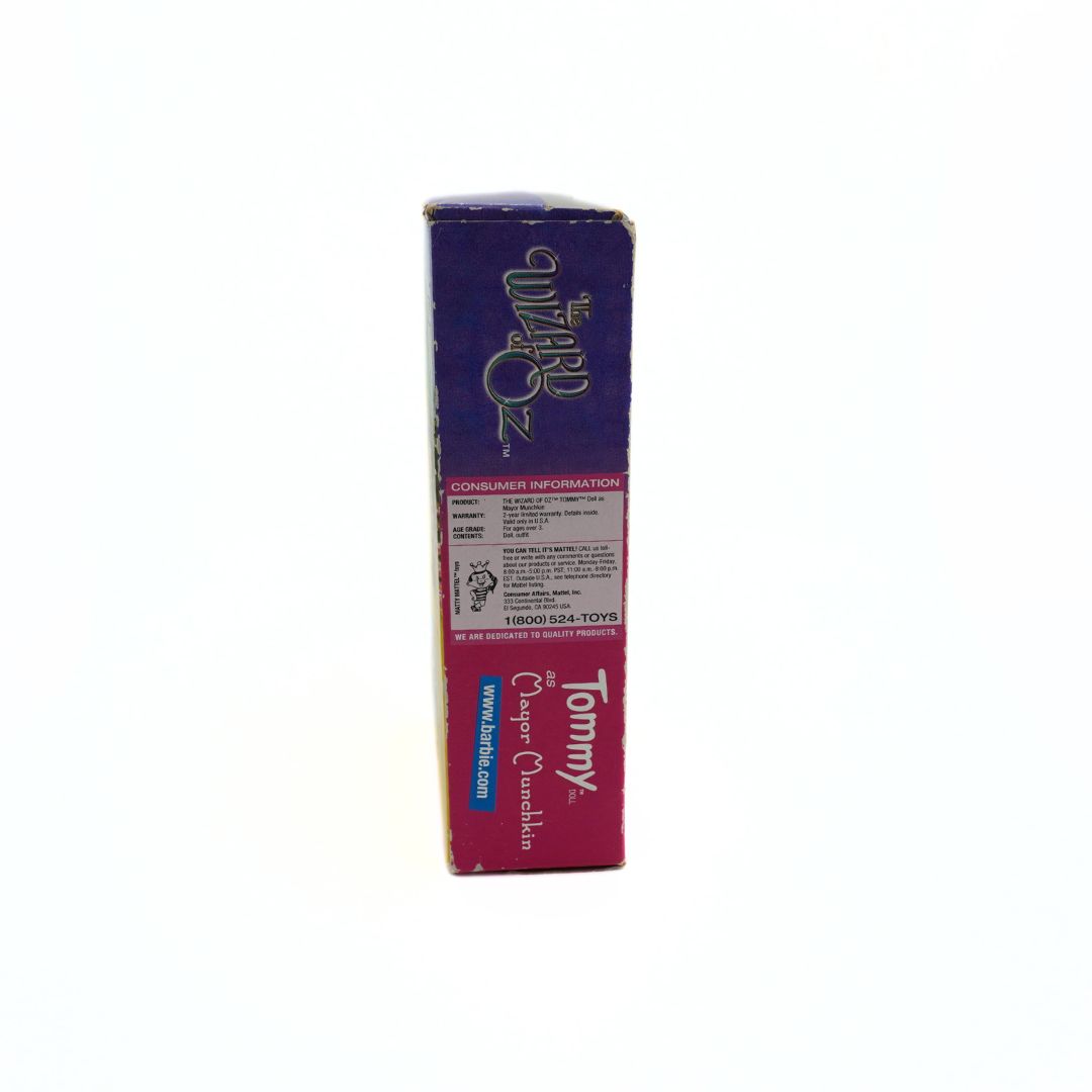 Side on photo of the pink and purple box of the Tommy as Mayor Munchkin Barbie doll showing the consumer information