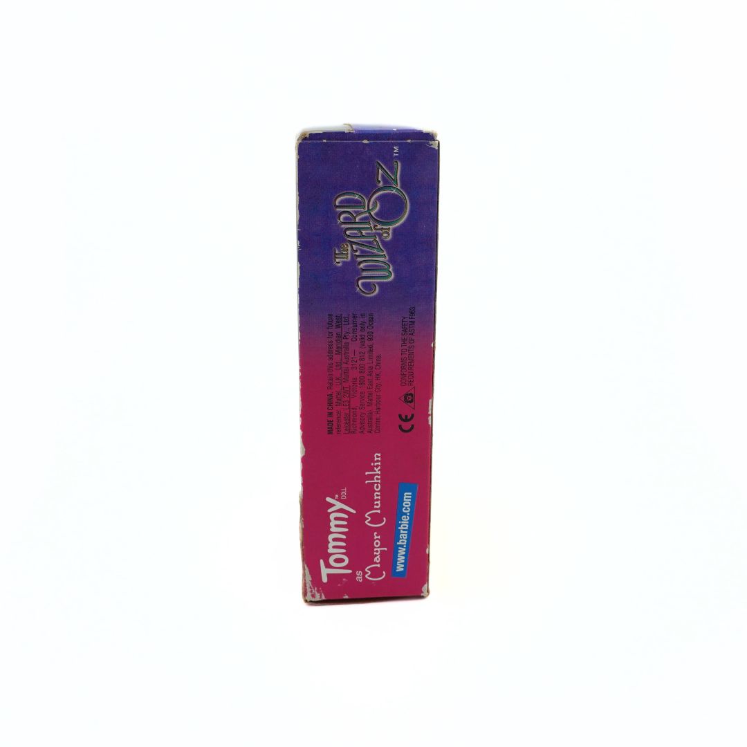 Side on photo of the pink and purple box of the Tommy as Mayor Munchkin Barbie doll