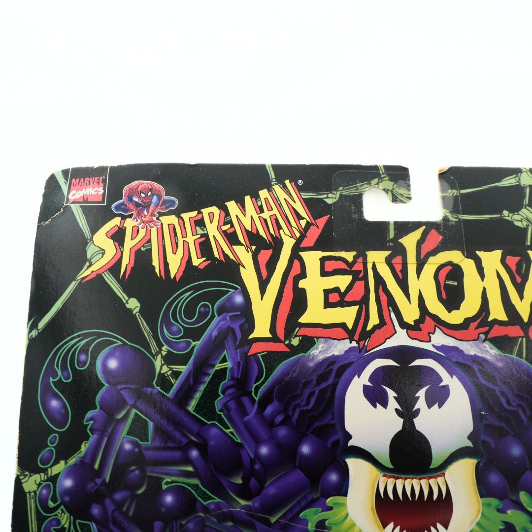 Top corner on the front of a vintage Venom figurine cardback showing some creasing