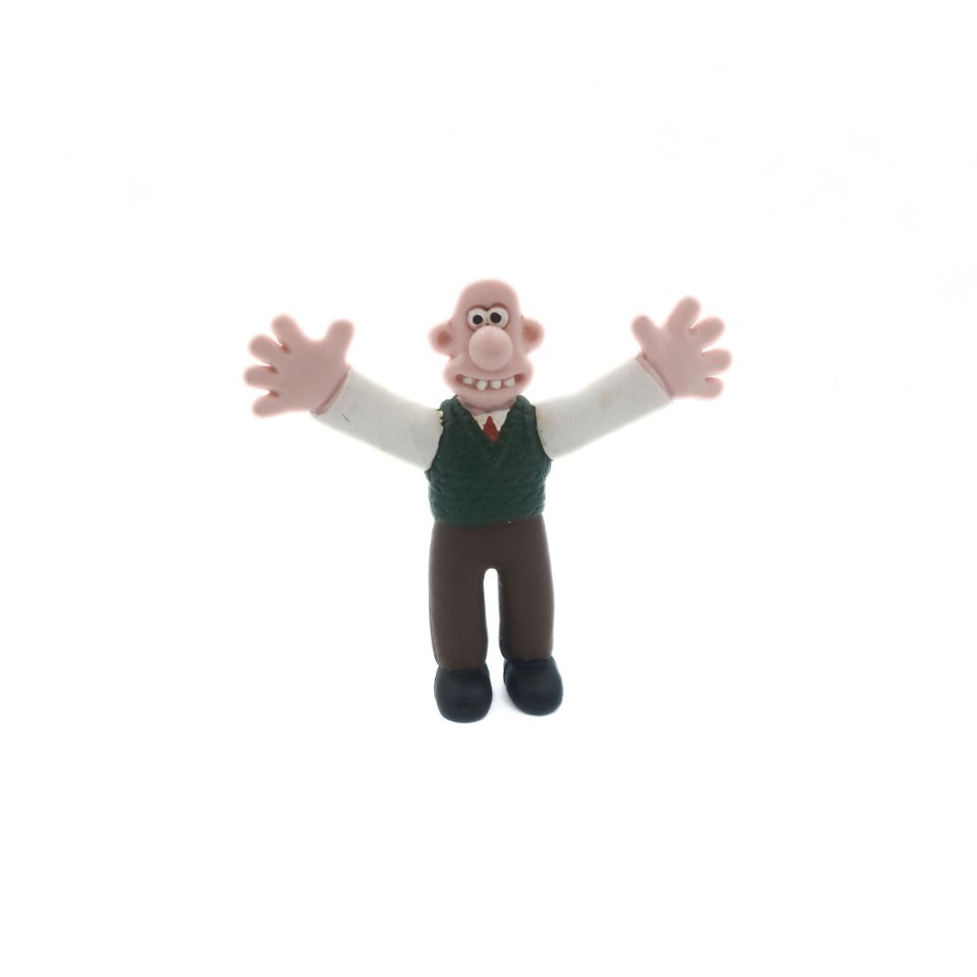 A vintage Wallace & Gromit figure of Wallace wearing a green vest and brown pants