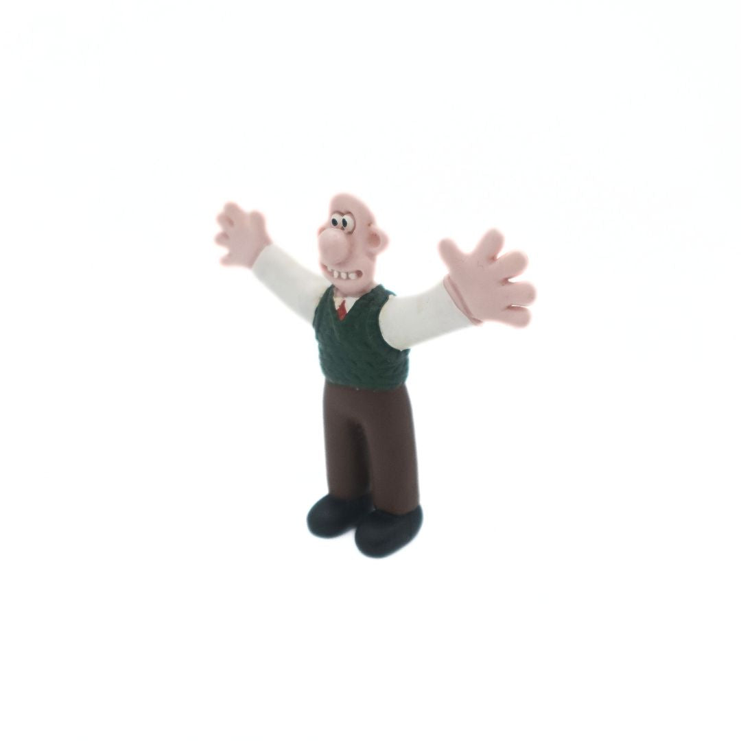 A vintage Wallace & Gromit figure of Wallace wearing a green vest and brown pants