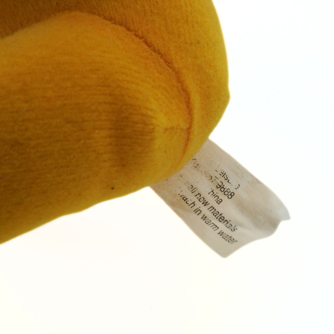 Close-up of a yellow plush toy with a label on a white background