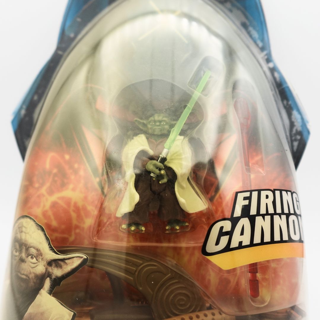 Closeup of a Yoda figurine with a green lightsaber inside its plastic figurine
