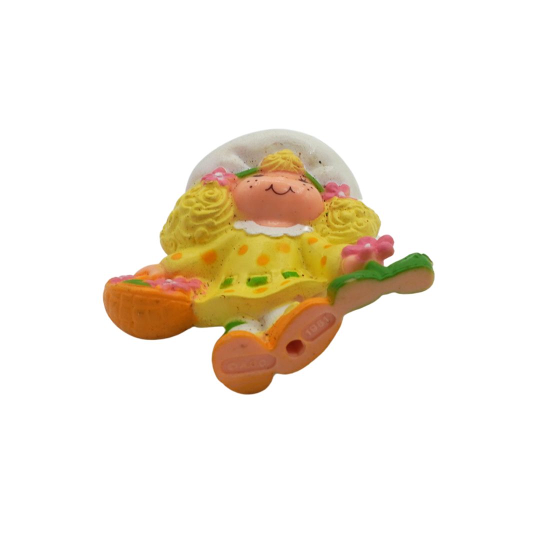 Toy figure of a baby in a yellow outfit with flowers on a white background