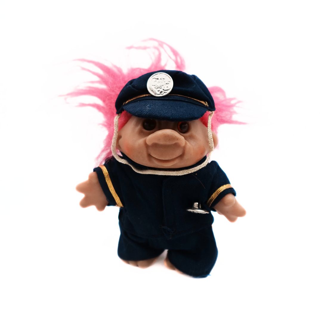 A 1986 Dam branded Policeman Troll Doll with pink hair, and a blue and gold uniform