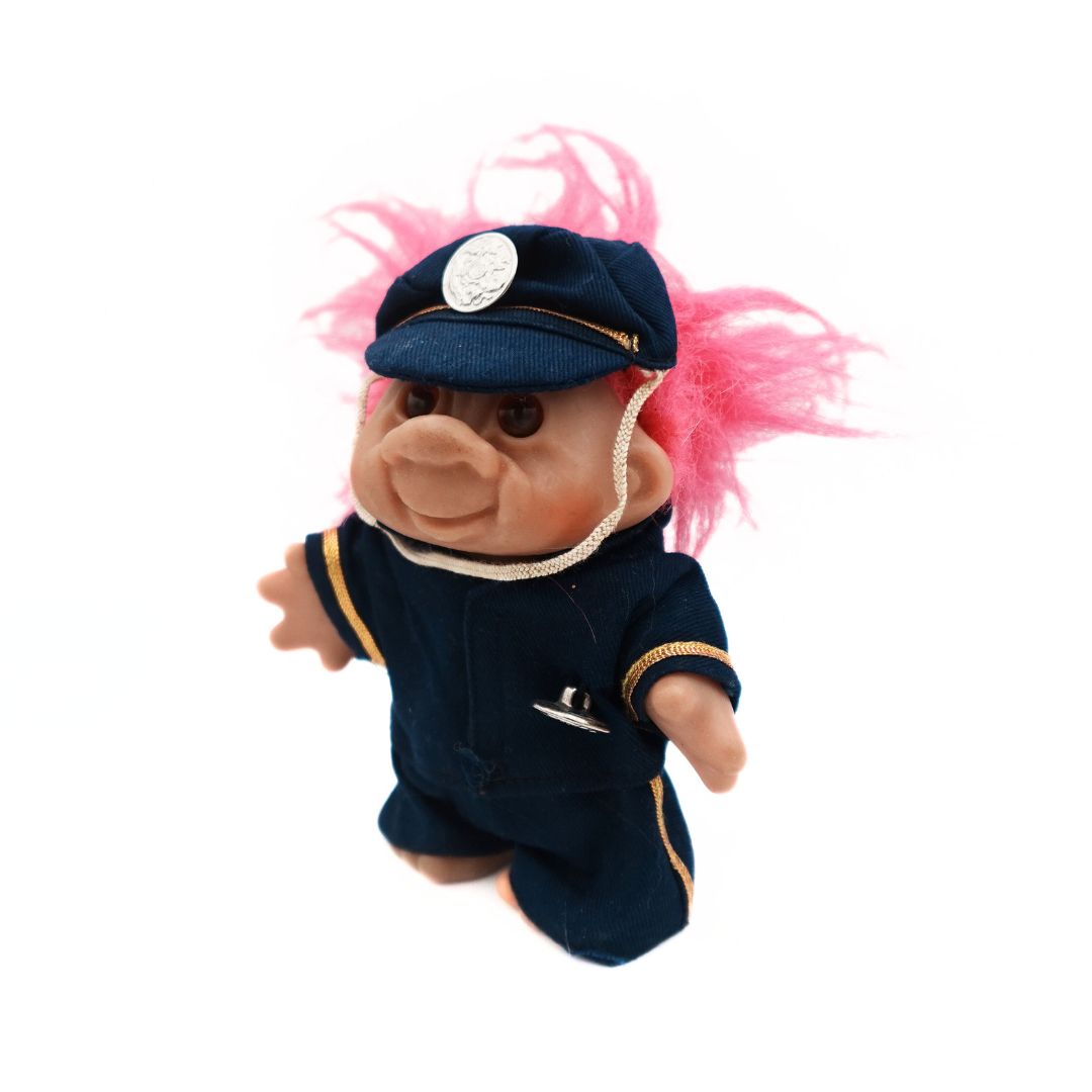 A 1986 Dam branded Policeman Troll Doll with pink hair, and a blue and gold uniform