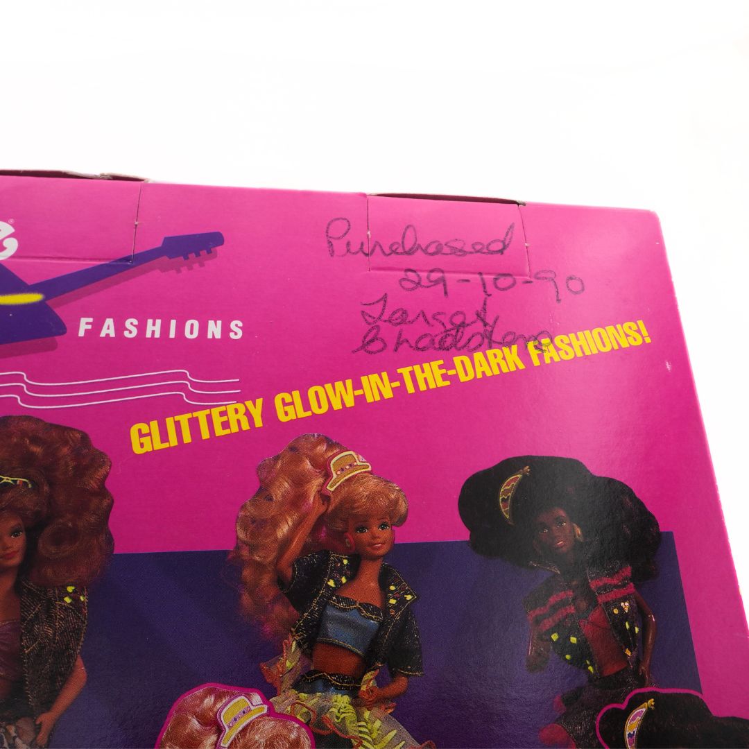 Vintage packaging for doll fashions with 'glittery glow-in-the-dark' text on a pink background.